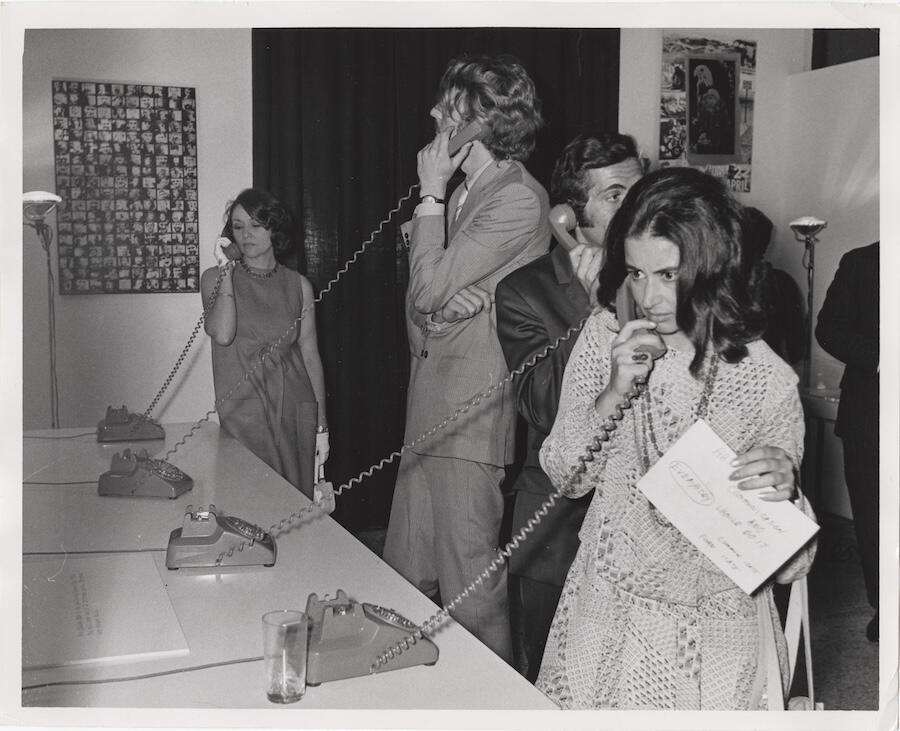 Black and white image of a woman who holds rotary phone to ear