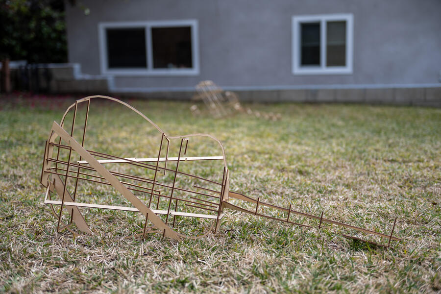 A couple of empty-bodied acoustic guitars strewn across a lawn in front of a house