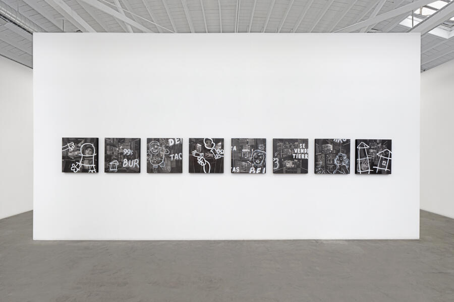 A row of black and white paintings in a row against the wall. They feature thick, grafitti-like lines, and they are in greyscale