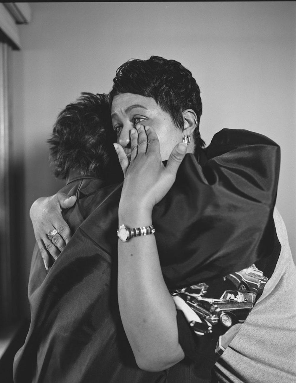 LaToya Ruby Frazier, Kesha Scales, UAW Local 1714, hugging her best friend and former co-worker, Beverly Williams, in her living room, (22 years in at GM Lordstown Complex pressroom), Youngstown, OH, 2019