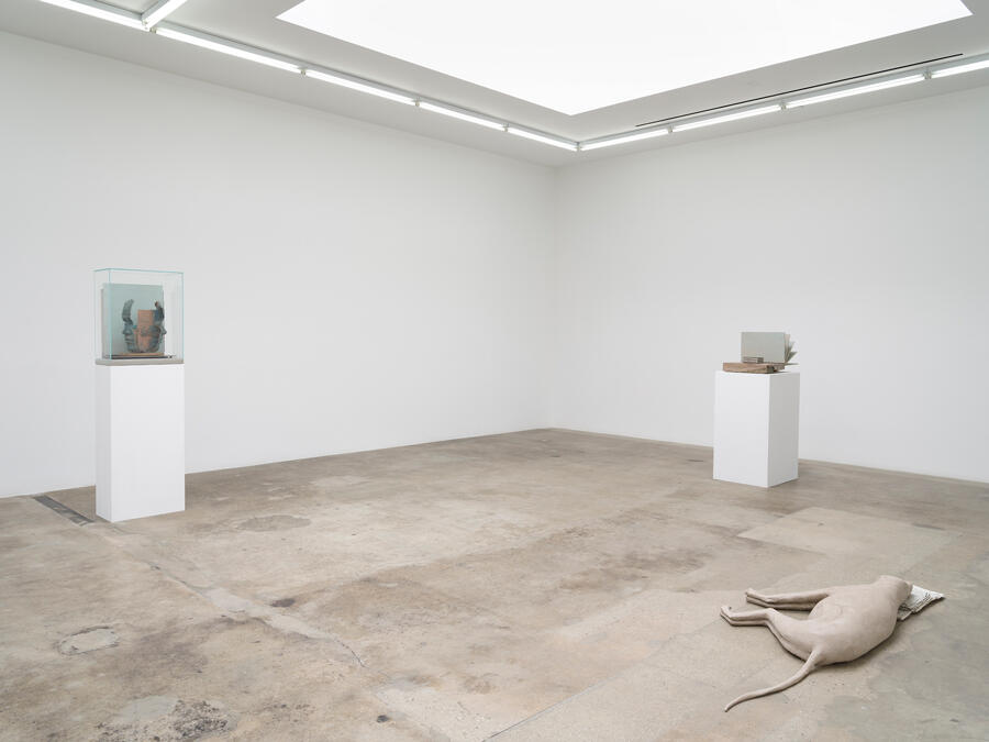 A gallery space with a sleeping dog sculpture, open book sculpture, and sculpture with faces