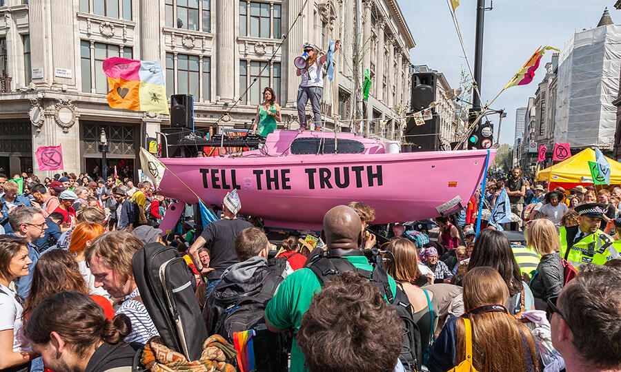 climate change protesters holding a pink boat with the sign 'tell the truth'.