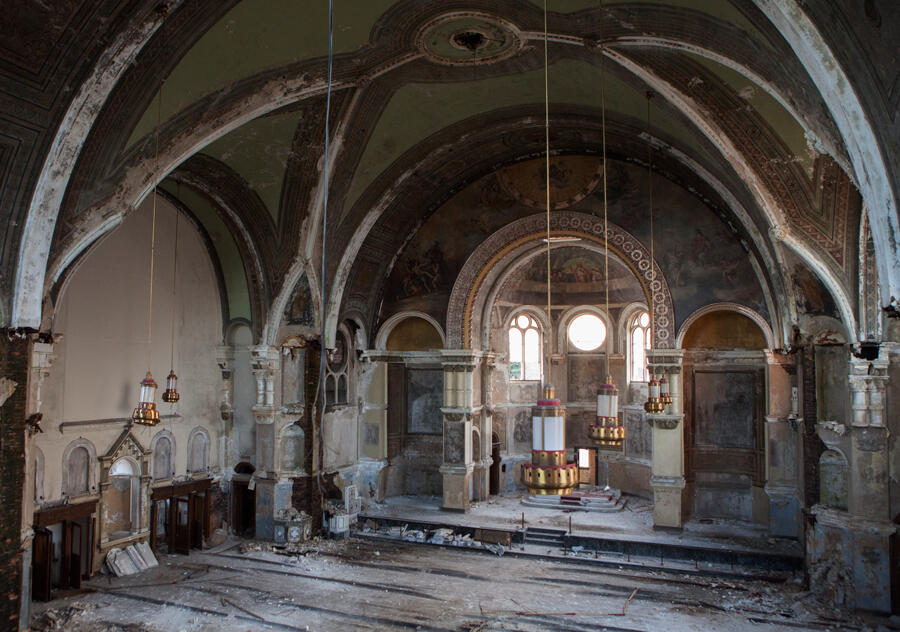 A derelict cathedral with hanging golden sculptures from the ceiling